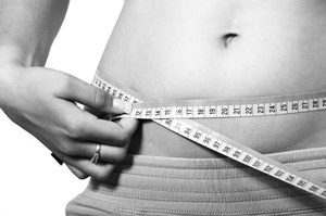 A girl is measuring her waist with a tap