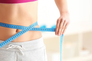 a woman is measureing her waistline