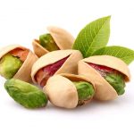 Pistachios with leaves on white background.