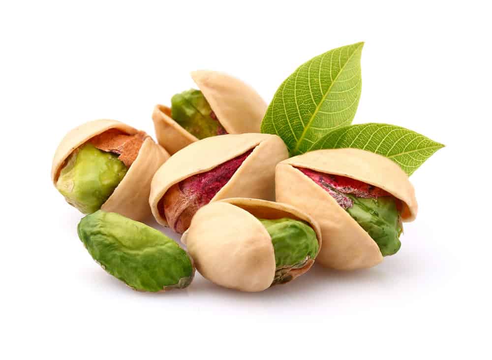 Pistachios with leaves on white background.