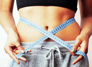 Woman measuring waist with tape on knot like a gift.