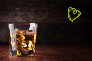 A glass of whiskey with a green drawing heartshape