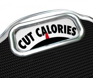 Cut Calories words on a scale display to illustrate dieting to eat less and lose weight.