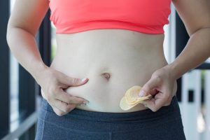 A fat woman with potato fries in the hands