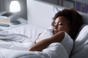 Young african woman sleeping in her bed at night, she is resting with eyes closed.