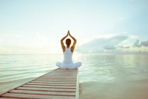 Woman practicing yoga at seashore