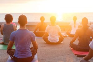 Group of people doing yoga under sunset